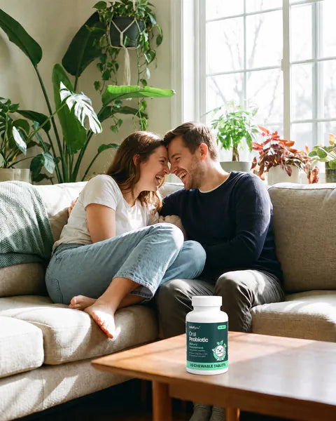 A couple cuddles on a sofa in a bright living room, a bottle of Oral Probiotic on the coffee table.